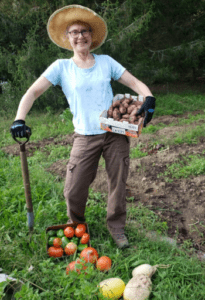 Heidi poses with potatoes, tomatoes and squash from her garden.