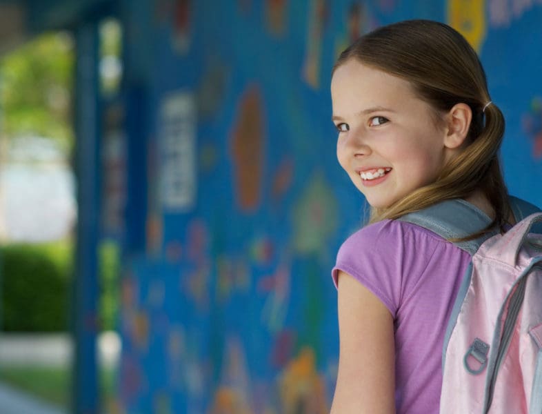 kid smiling and looking over her shoulder