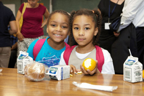 young girls eating breakfast with milk