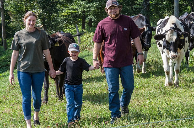 Farmer family walking in cow pasture