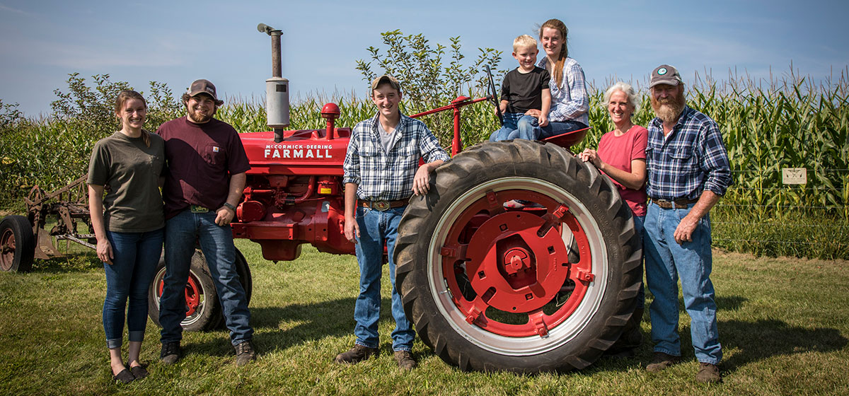 Farm family posting in front of red tractor