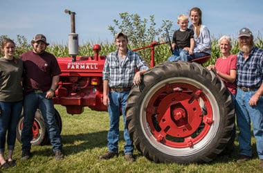 Farm family posting in front of red tractor