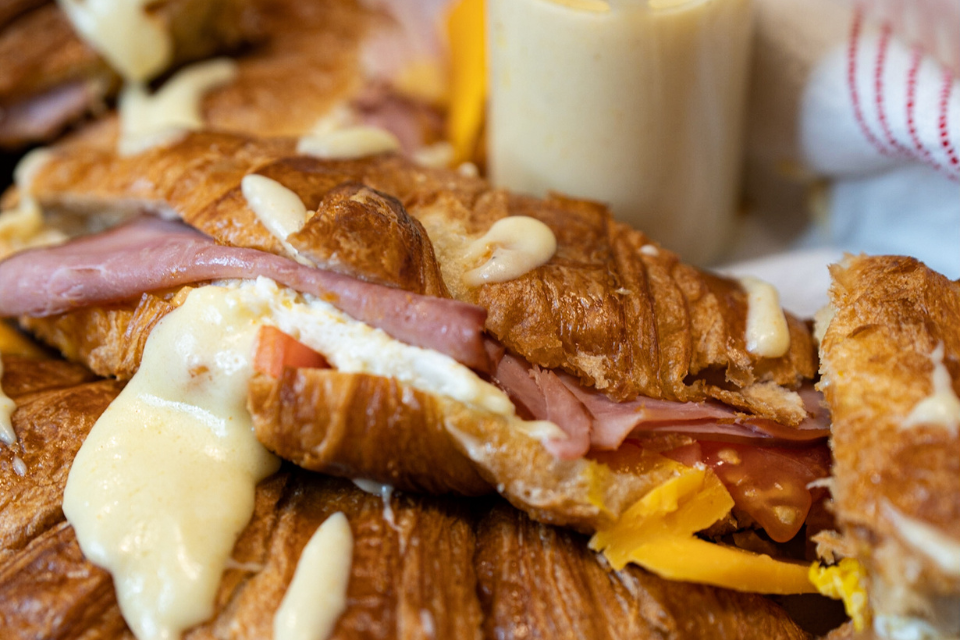Cheesy croissants with ham, eggs, cheese, tomato with a cheese sauce.