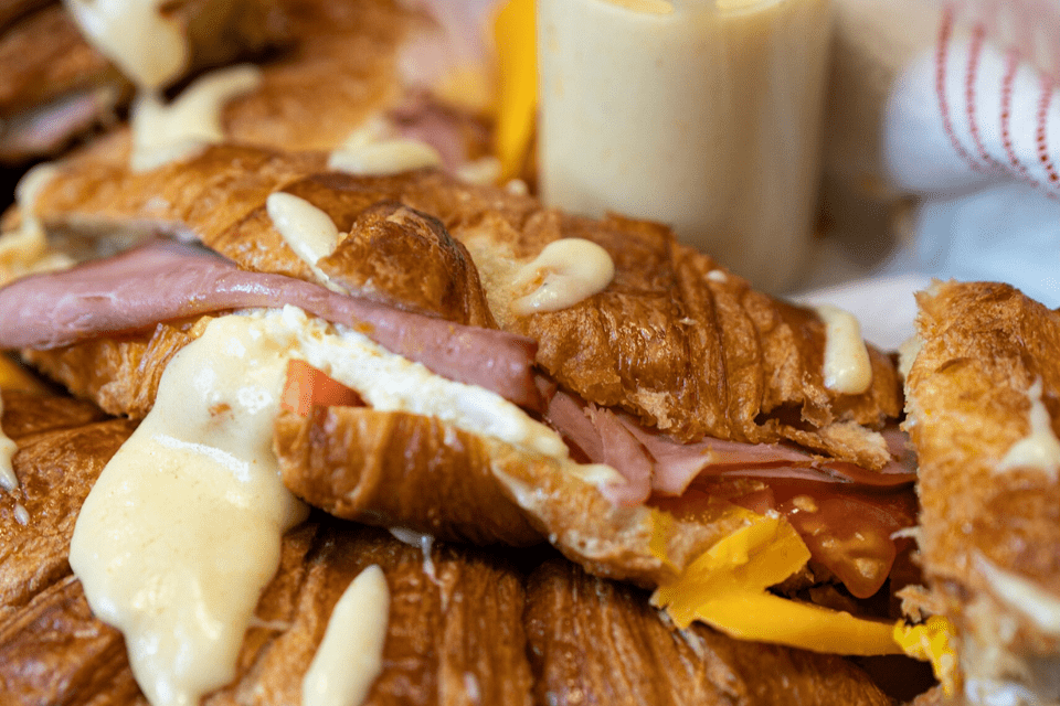 Cheesy croissants with ham, eggs, cheese, tomato with a cheese sauce.