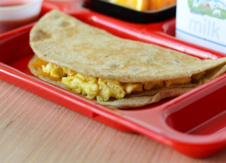 Egg and cheese quesadilla on tray with milk carton and orange slices
