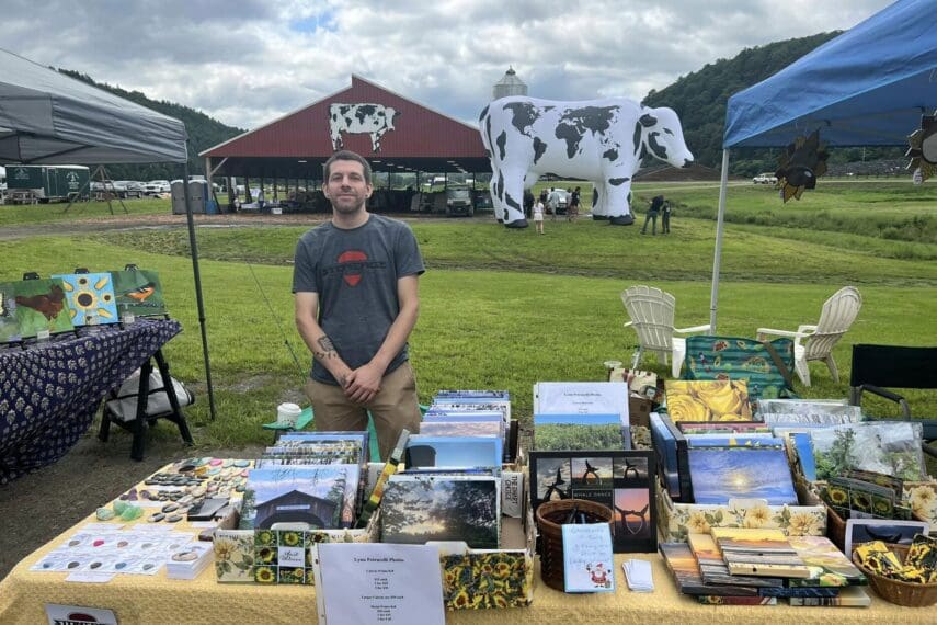 Man on a farm with table full of art